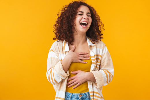 Junge Frau lacht herzlich – denn Lachen ist gesund!